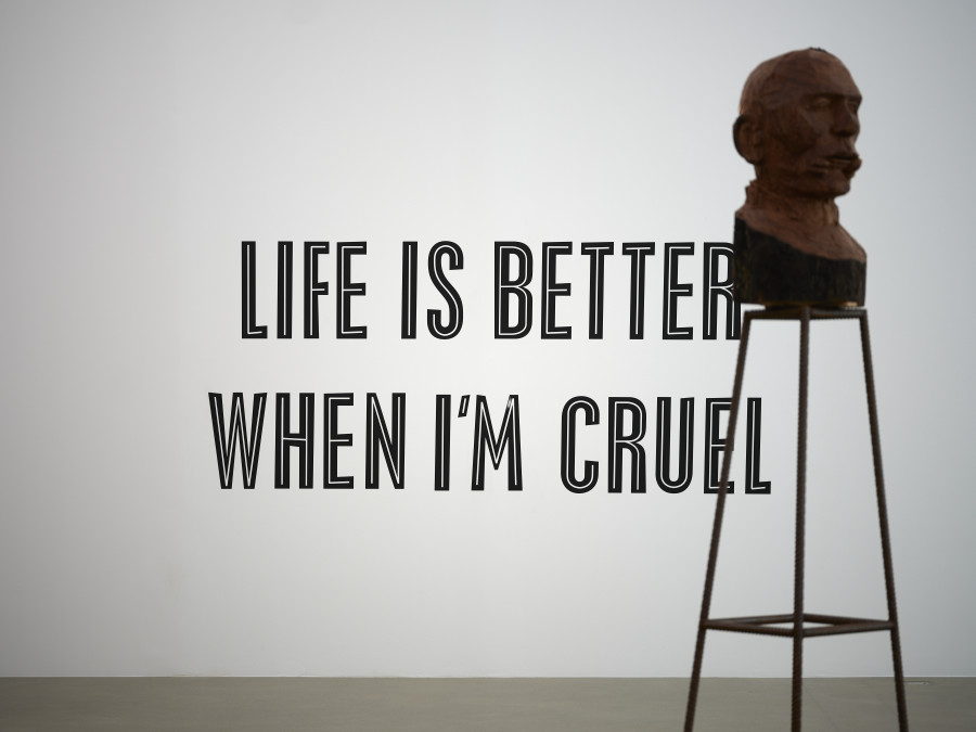 lnstallationsansicht Stranger in the Village, Rassismus im Spiegel von James Baldwin, 3.9.2023 - 7.1.2024, Aargauer Kunsthaus. Martine Syms, Lite is Better When l'm Cruel, 2016, Farbe auf Wand. Sammlung Ringier, Schweiz. Kader Attia, Culture, Another Nature Repaired, 2014, Teakholz auf Metallsockel, 72 x 40 x 40 cm. Kunstmuseum Bern, Sammlung Stiftung GegenwART Foto: David Aebi, Bern