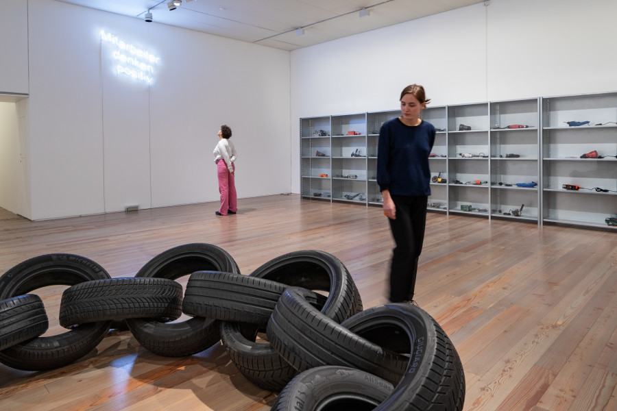 Installation view Delphine Reist. ÔL [oil, olio, huile] at Museum Tinguely, Basel, 2023, Delphine Reist, Collier [necklace], 2014 (front), Delphine Reist, Mitarbeiter denken positiv, 2017 (hinten links), Courtesy Delphine Reist, Galerie Lange+ Pult, Galerie Laurent Godin , Delphine Reist, Étagères [shelves], 2007 (back, right), Collection Institut d'art contemporain de Villeurbanne/ Rhône-Alpes, © Delphine Reist, Photo: Museum Tinguely, Base!; Bettina Matthiessen